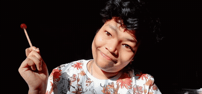 A Young Man Is Holding A Lollipop In His Hand . GIF