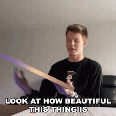 A Young Man Is Holding A Piece Of Paper With The Words Look At How Beautiful This Thing Is Below Him GIF