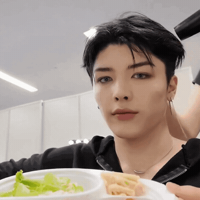 A Young Man Is Holding A Plate Of Food With A Salad And French Fries On It GIF
