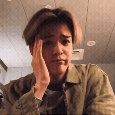 A Young Man Is Holding His Hand To His Forehead And Making A Sad Face . GIF