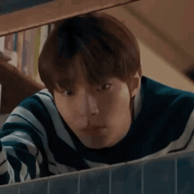 A Young Man Is Looking Out Of A Window . GIF