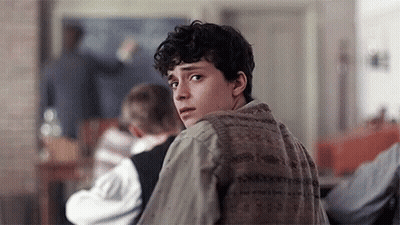 A Young Man Is Looking Over His Shoulder In A Classroom . GIF