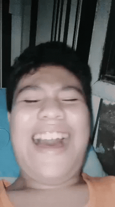A Young Man Is Making A Funny Face While Laying On A Bed . GIF