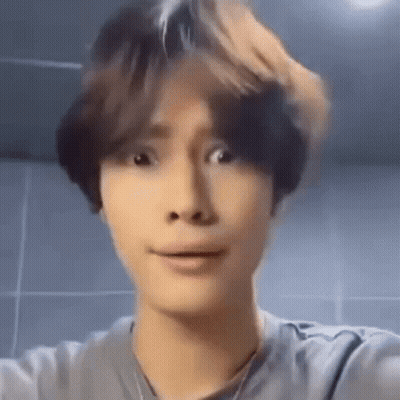 A Young Man Is Making A Funny Face While Taking A Selfie In Front Of A Mirror . GIF