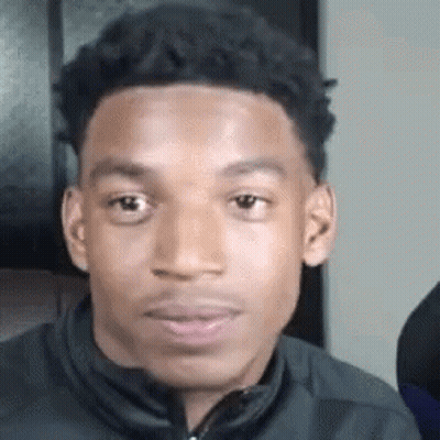 A Young Man Is Making A Funny Face While Wearing A Jacket . GIF