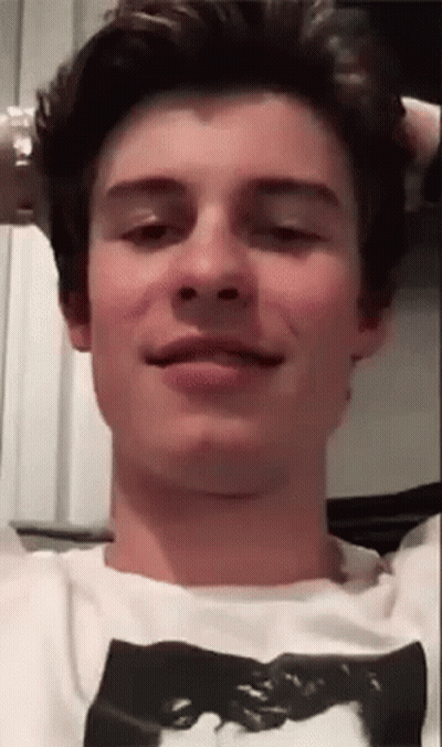 A Young Man Is Making A Funny Face While Wearing A White T-Shirt With A Picture On It . GIF