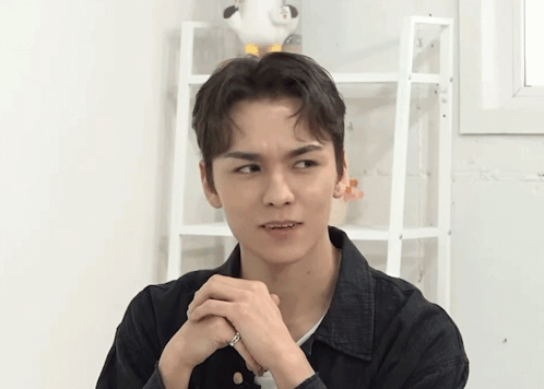 A Young Man Is Making A Funny Face With His Hands Folded GIF