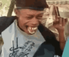 A Young Man Is Making A Funny Face With His Tongue Out And A Hat On . GIF