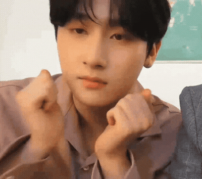 A Young Man Is Making A Heart Shape With His Hands While Looking At The Camera . GIF