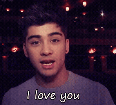 A Young Man Is Saying I Love You In Front Of A Dark Background GIF