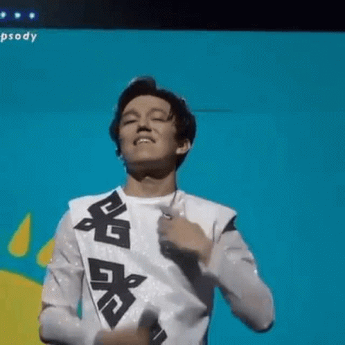 A Young Man Is Singing Into A Microphone On A Stage And Dancing . GIF