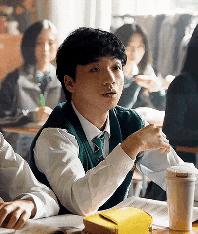 A Young Man Is Sitting At A Desk In A Classroom . GIF