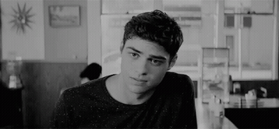 A Young Man Is Sitting At A Table In A Diner Looking At The Camera . GIF