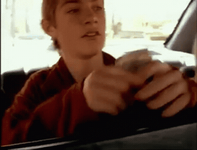 A Young Man Is Sitting In A Car Holding A Bunch Of Money . GIF