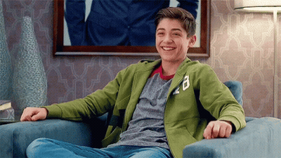 A Young Man Is Sitting In A Chair Smiling . GIF