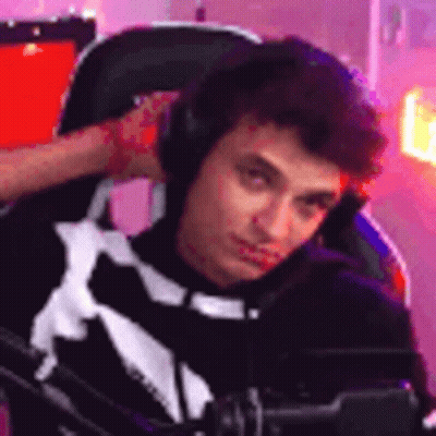 A Young Man Is Sitting In A Chair Wearing Headphones And Looking At The Camera . GIF