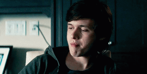 A Young Man Is Sitting In A Chair With His Eyes Closed And Making A Funny Face . GIF