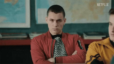 A Young Man Is Sitting In A Classroom With His Arms Crossed . GIF