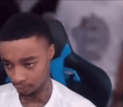 A Young Man Is Sitting In A Gaming Chair Looking At The Camera . GIF