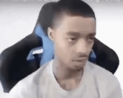 A Young Man Is Sitting In A Gaming Chair With A Blue Pillow . GIF