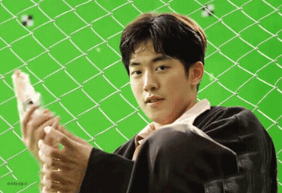 A Young Man Is Sitting In Front Of A Chain Link Fence Holding A Bottle Of Water . GIF