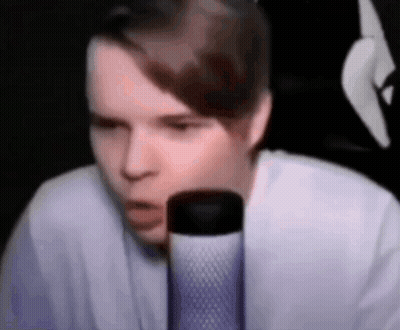 A Young Man Is Sitting In Front Of A Microphone . GIF