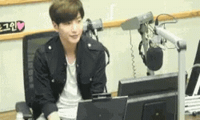 A Young Man Is Sitting In Front Of A Microphone In Front Of A Computer Monitor .. GIF