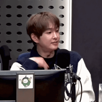 A Young Man Is Sitting In Front Of A Microphone In Front Of A Computer Monitor . GIF