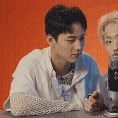 A Young Man Is Sitting In Front Of A Microphone . GIF