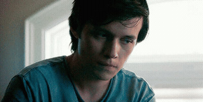 A Young Man Is Sitting In Front Of A Window Looking Down . GIF