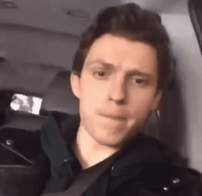 A Young Man Is Sitting In The Back Seat Of A Car And Making A Funny Face . GIF