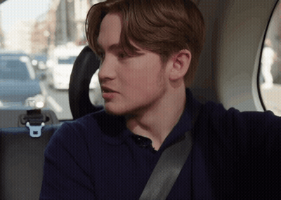 A Young Man Is Sitting In The Back Seat Of A Car With A Seat Belt Around His Neck GIF
