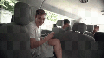 A Young Man Is Sitting In The Back Seat Of A Van Looking At His Cell Phone . GIF