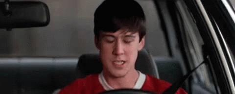 A Young Man Is Sitting In The Driver 'S Seat Of A Car With His Eyes Closed . GIF