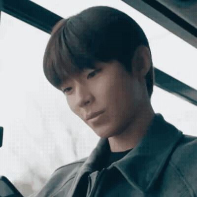A Young Man Is Sitting On A Bus And Looking At His Phone . GIF