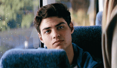 A Young Man Is Sitting On A Bus Looking Out The Window . GIF