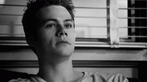 A Young Man Is Sitting On A Couch In Front Of A Window Looking Up . GIF