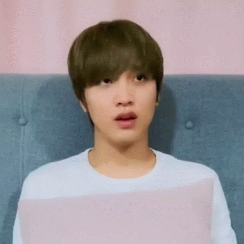 a young man is sitting on a couch with his mouth open .