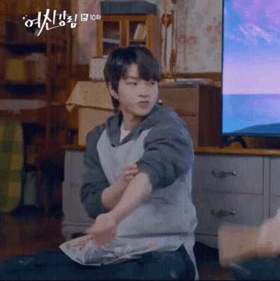 A Young Man Is Sitting On The Floor In Front Of A Television Holding A Piece Of Paper . GIF