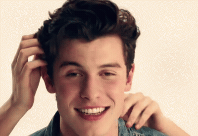 A Young Man Is Smiling And Scratching His Head . GIF