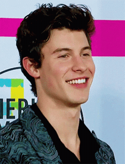 A Young Man Is Smiling In Front Of A Sign That Says ' Ier ' On It GIF