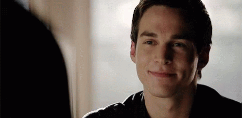 A Young Man Is Smiling While Looking At Another Person In A Mirror . GIF