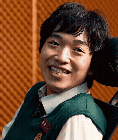 A Young Man Is Smiling While Sitting In A Wheelchair . GIF