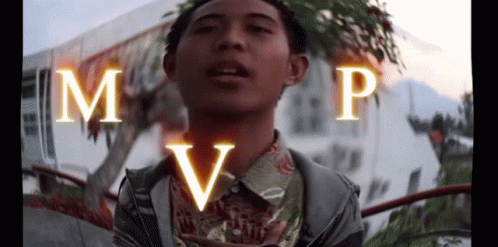 A Young Man Is Standing In Front Of A Building With The Letters M And P On His Chest .. GIF
