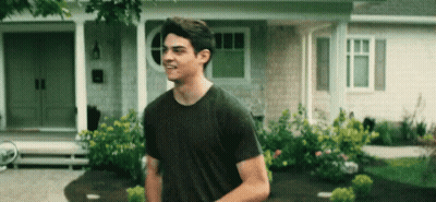 A Young Man Is Standing In Front Of A House . GIF