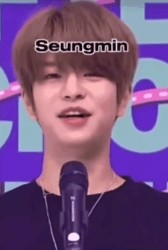 A Young Man Is Standing In Front Of A Microphone And Talking Into It . GIF