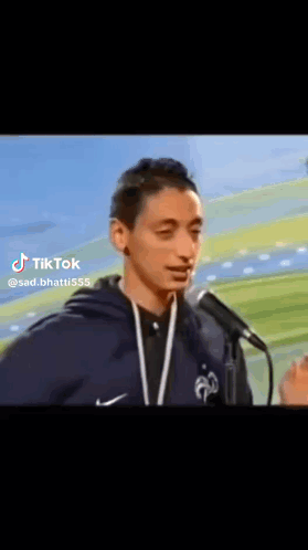 A Young Man Is Standing In Front Of A Microphone And Talking Into It . GIF