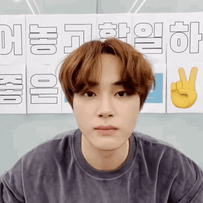A Young Man Is Standing In Front Of A Sign That Says ' Korean ' On It GIF