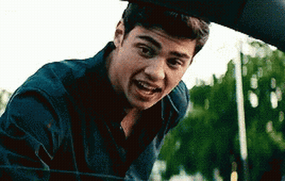 A Young Man Is Standing Next To A Car Looking Out The Window . GIF