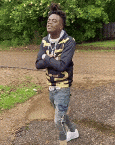 A Young Man Is Standing On A Dirt Road With His Arms Crossed And His Eyes Closed . GIF